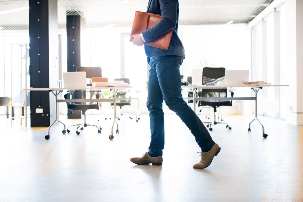 Male professional with briefcase walking by empty desks in an office signaling vacant positions that need to be filled