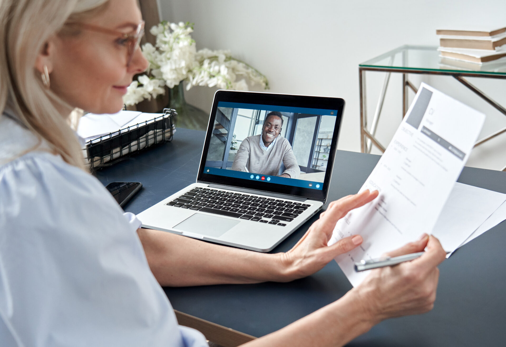 Female headhunter reading resume during online virtual job interview by video call on her laptop.