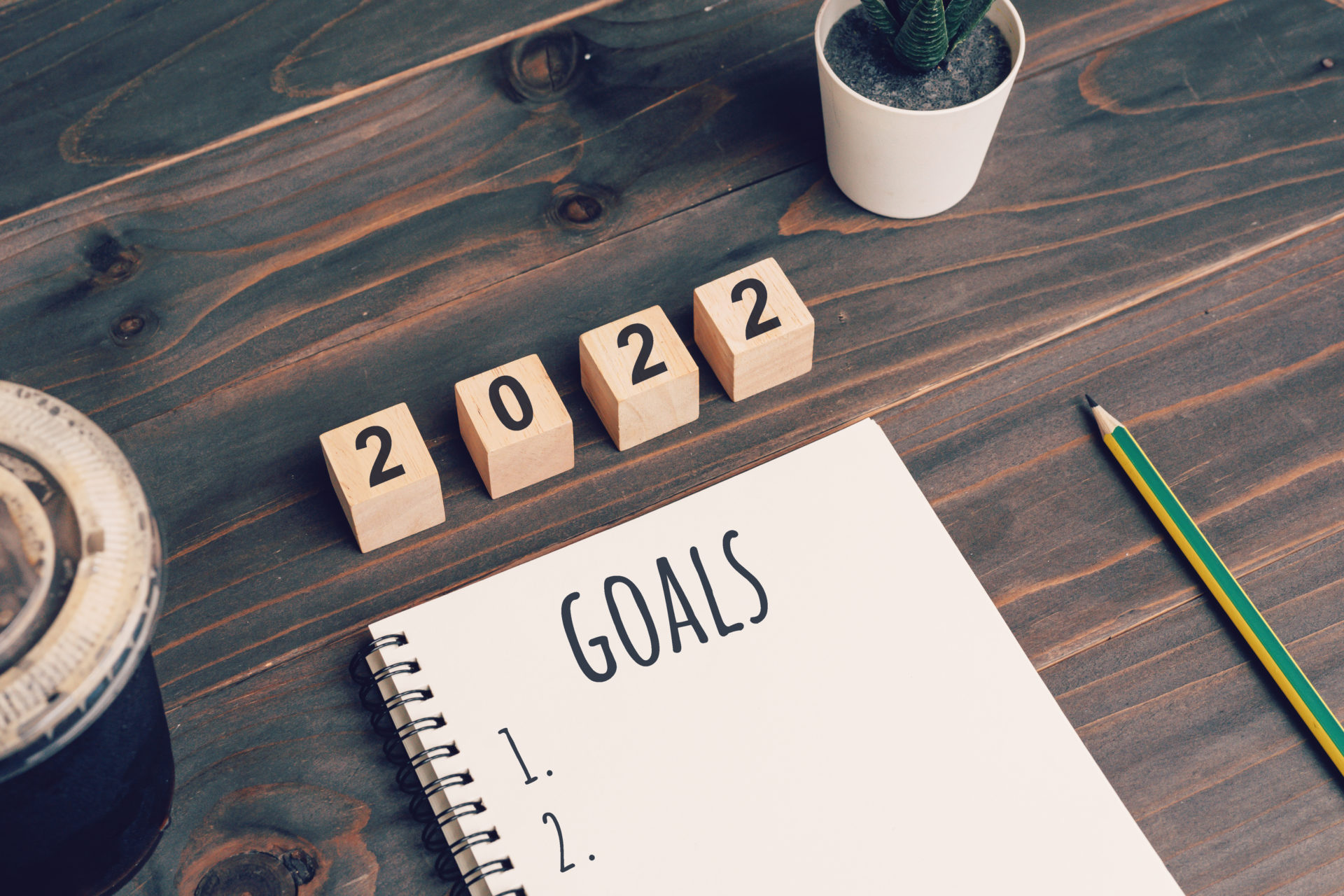 2022 goals text on notepad with coffee cup and pen on wooden desk