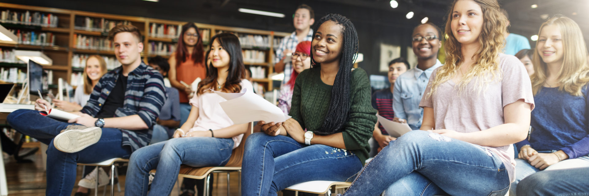 Group of students sitting in chairs listening and taking notes
