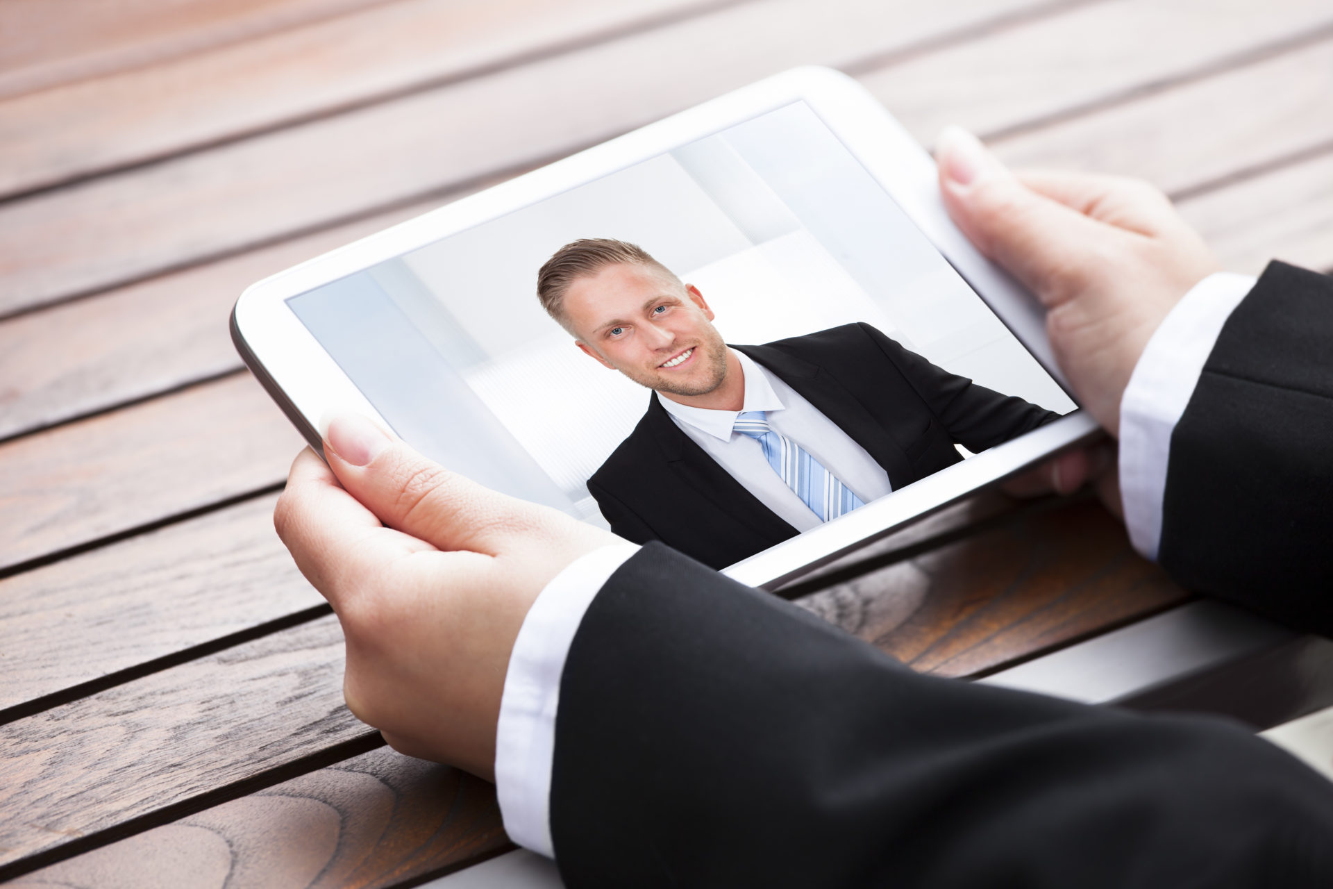 iPad being held with a male professional smiling on the screen
