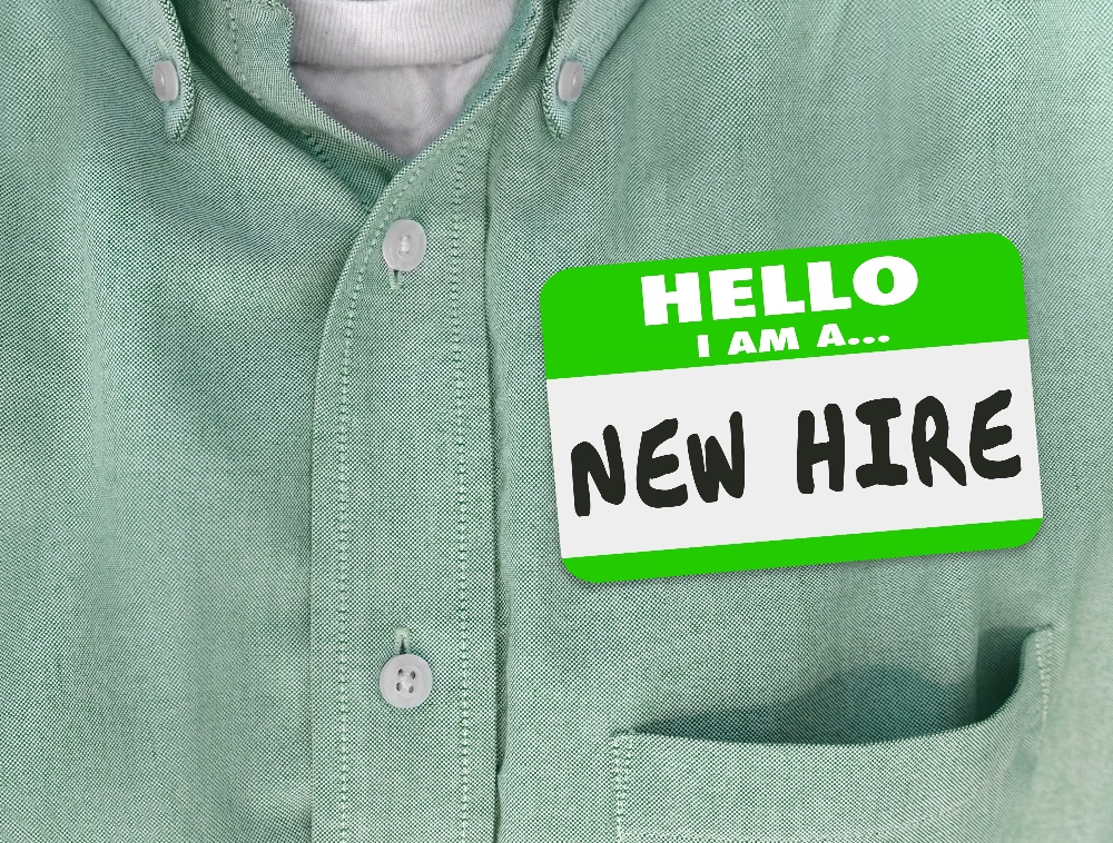 Green sticker on a shirt saying "Hello I am a... New Hire"