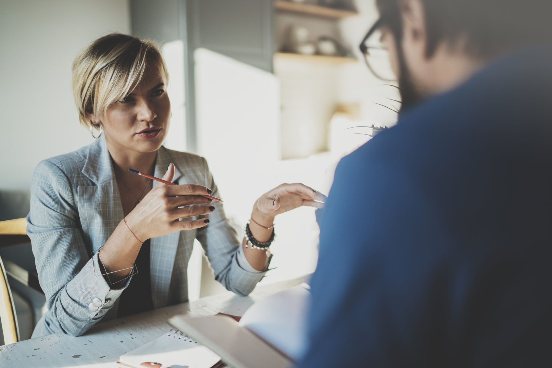 Female professional talking across the table holding a pencil
