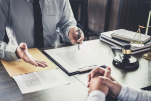 Two legal professionals sitting across from each other at a desk looking at paperwork
