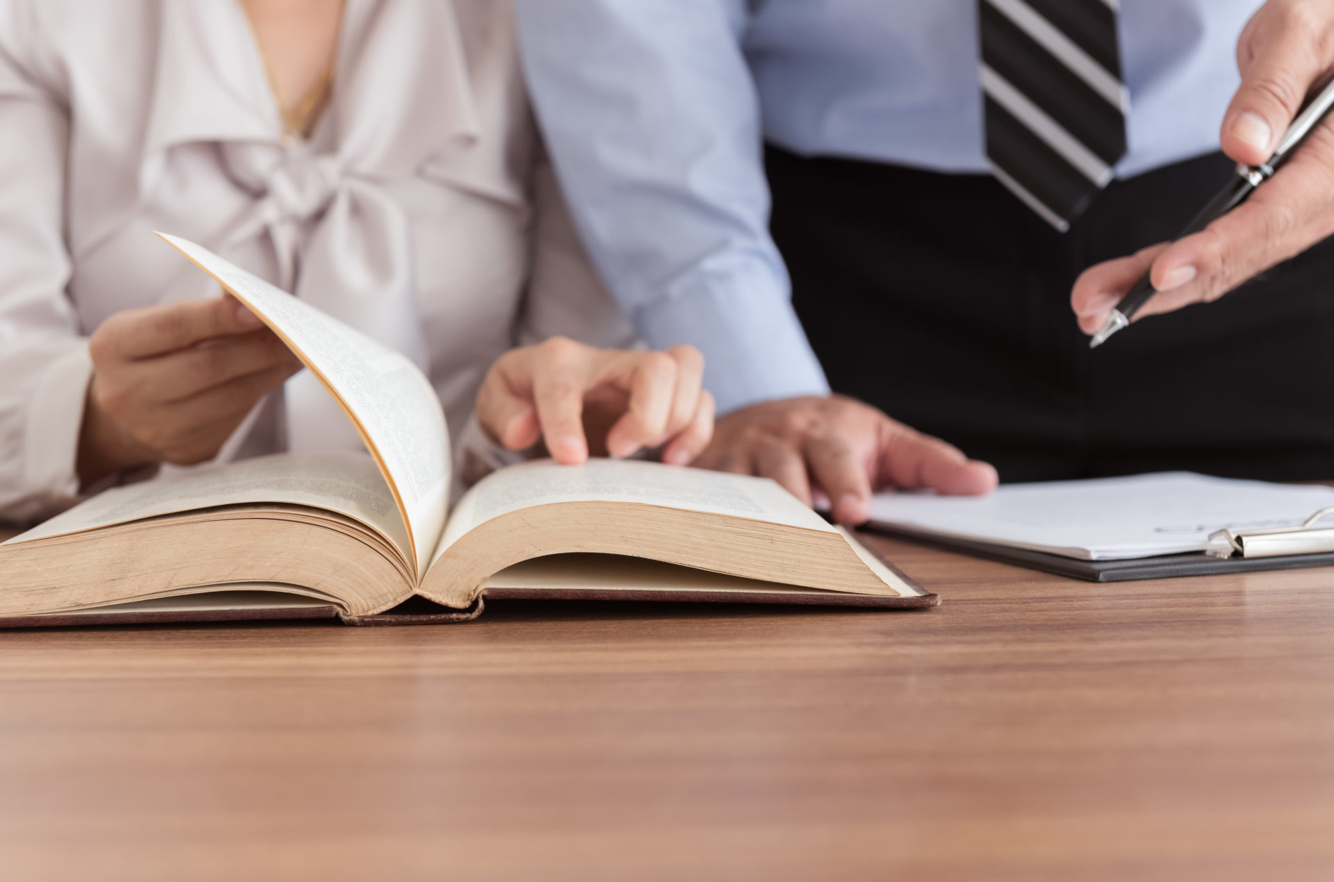 Two professionals looking through a legal book
