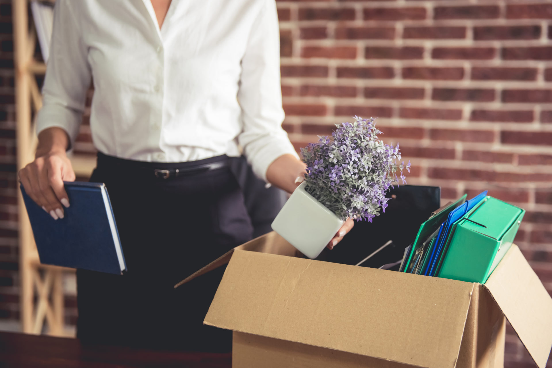 Female professional packing up the things in her office into a brown box