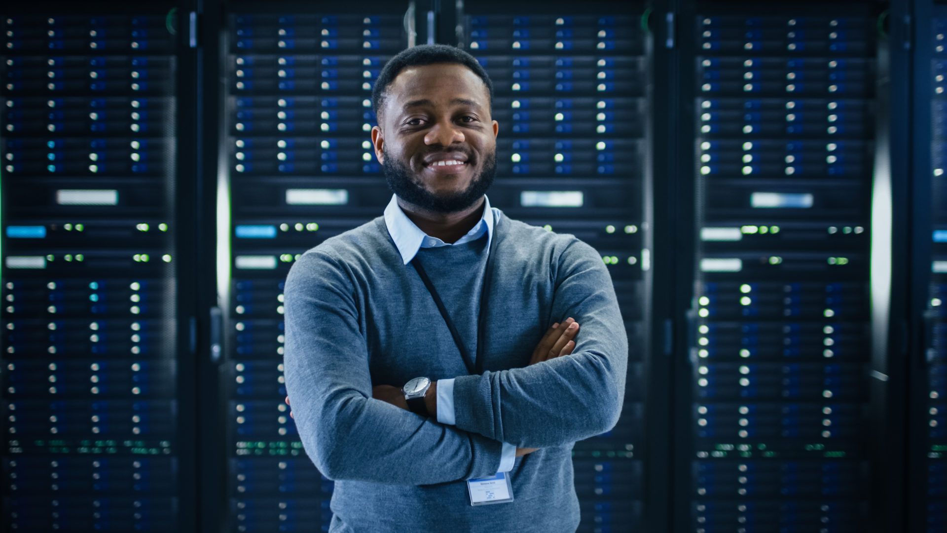 Male IT employee standing and smiling in a control room