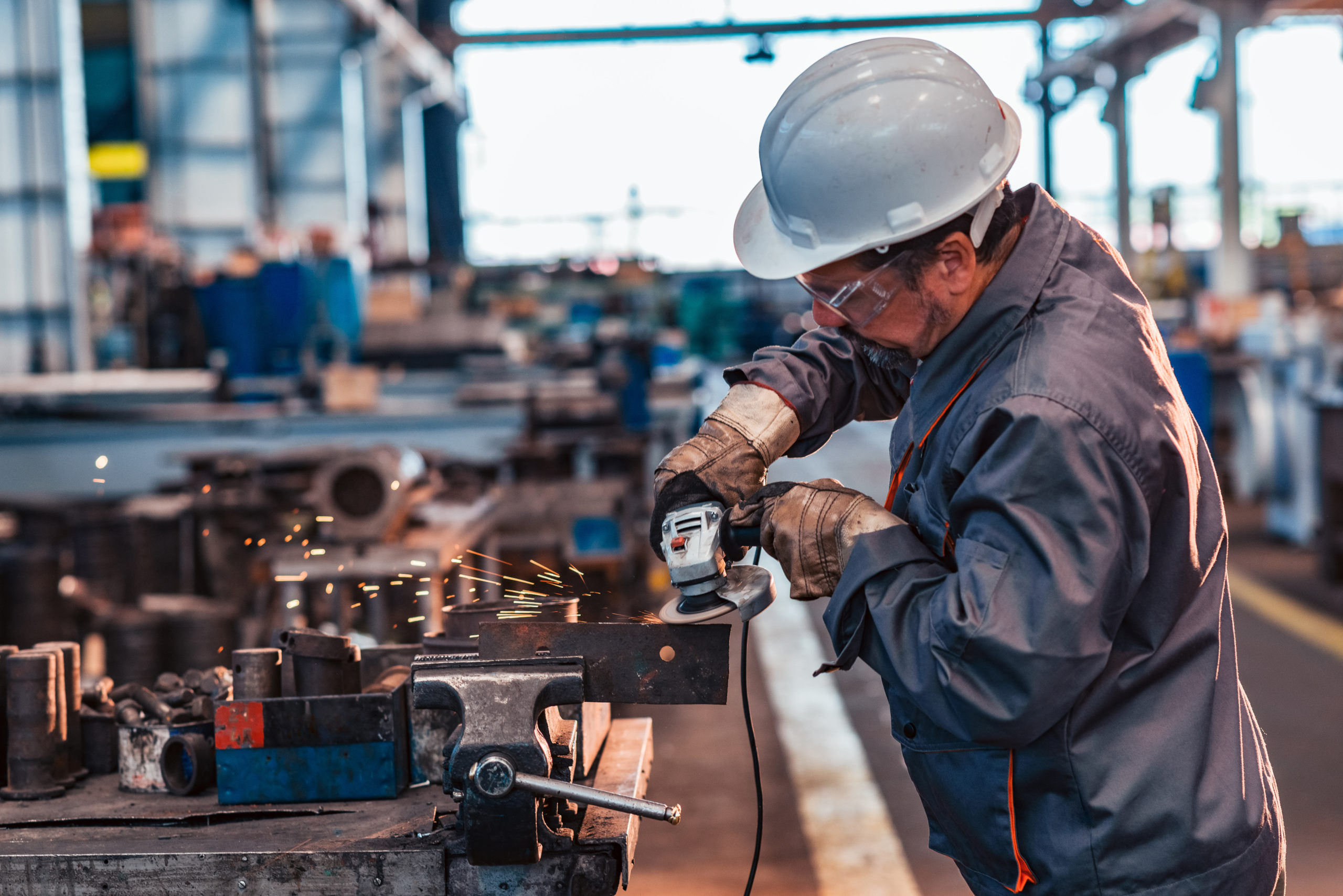 Skilled industrial worker grinding a metal part