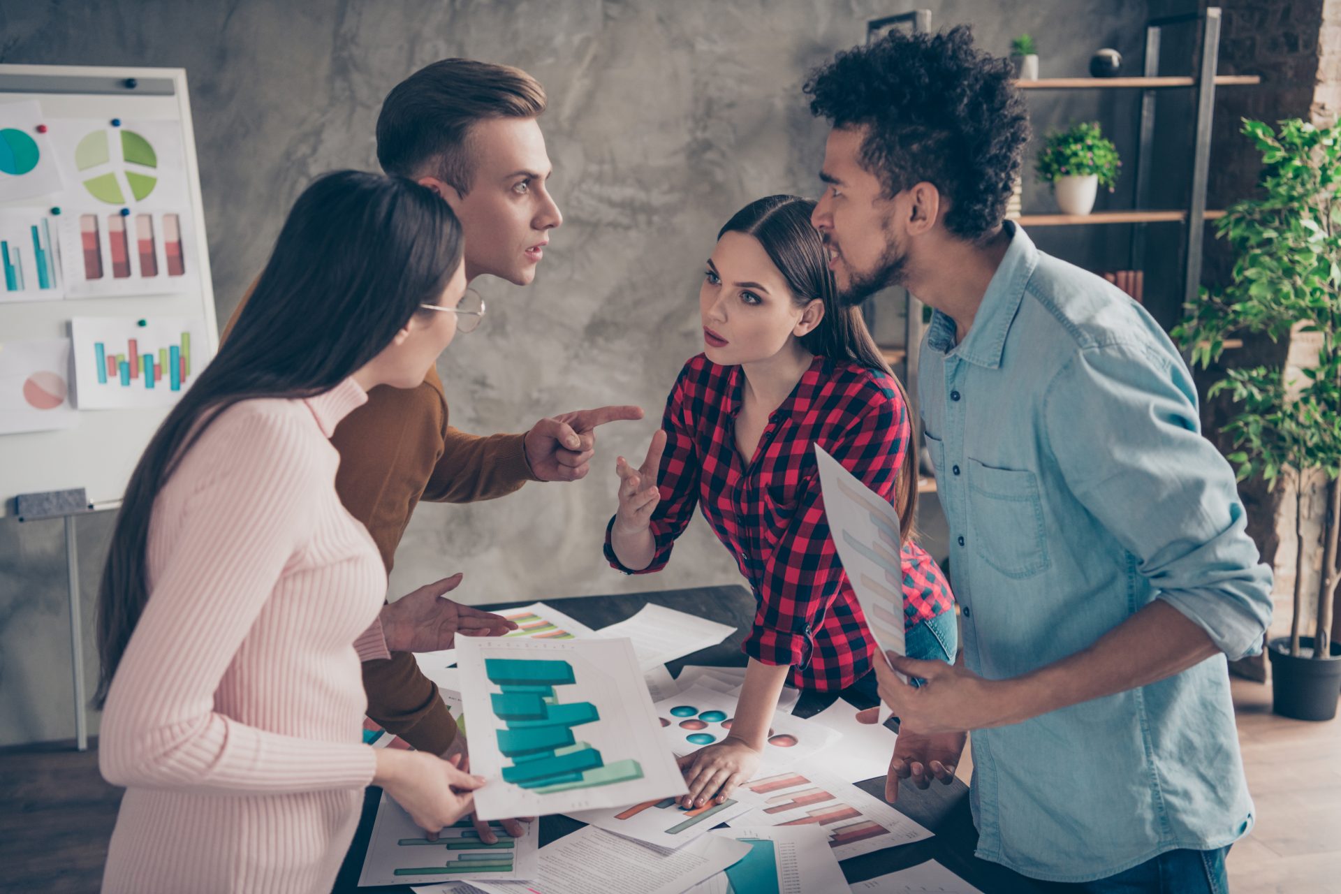 Four professionals disagreeing as they look over different graphs