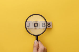 Magnifying glass held up to word blocks spelling out "Jobs"