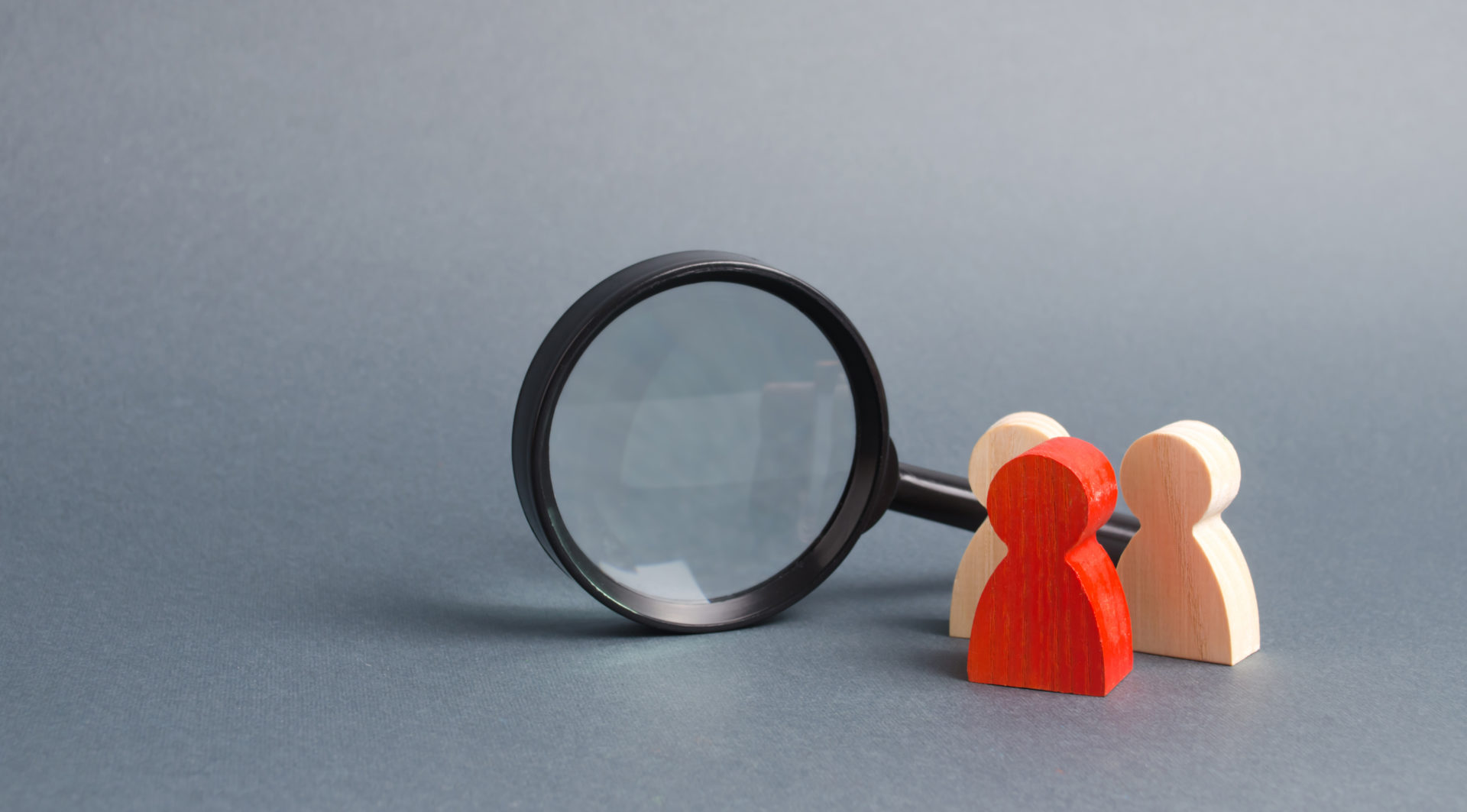 Wooden characters next to a magnifying glass