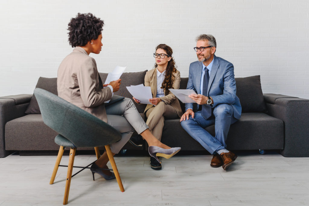 Two interviewees sitting on a couch with a female interviewer across from them in a chair