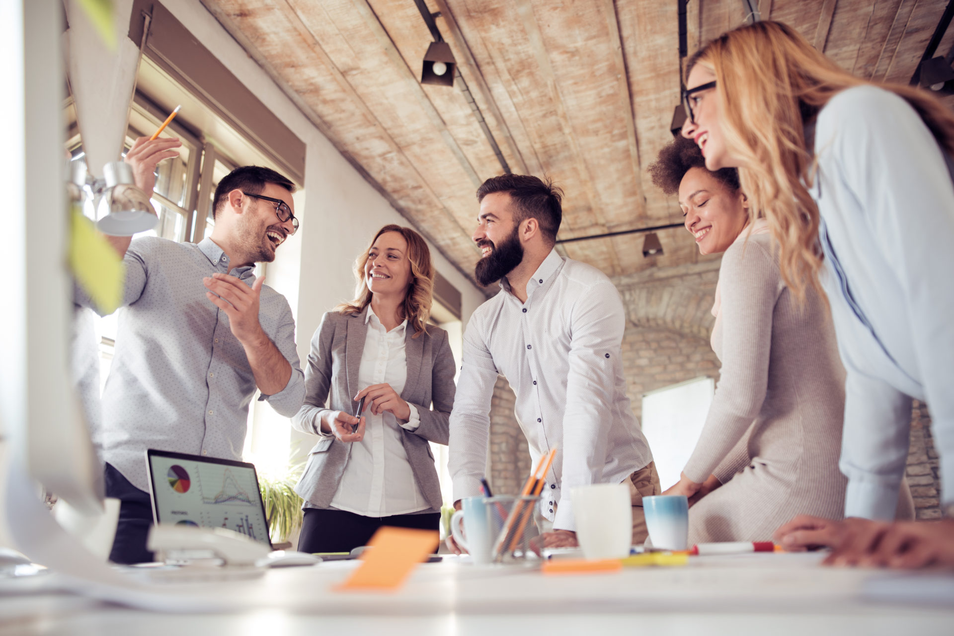 Team of five professionals surrounding a table with sticky notes chatting