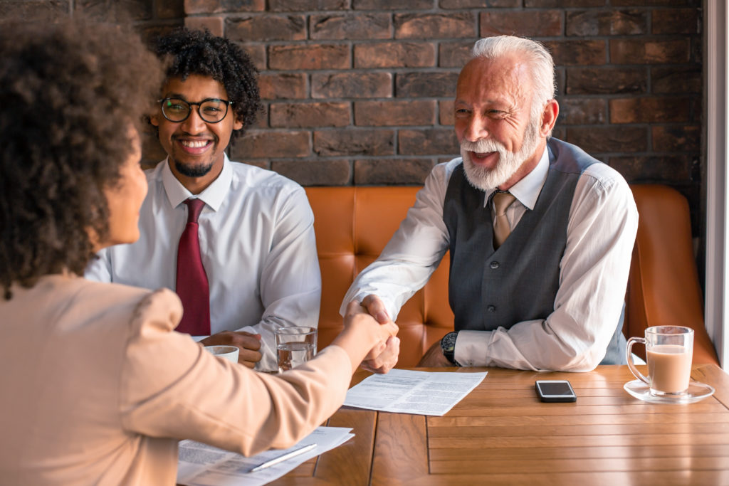 An elderly male and younger male sitting at a booth for a job interview