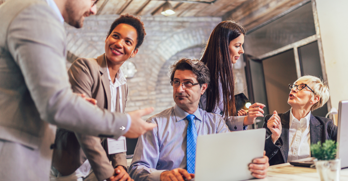 Age diverse professionals conversating around a desk in an office