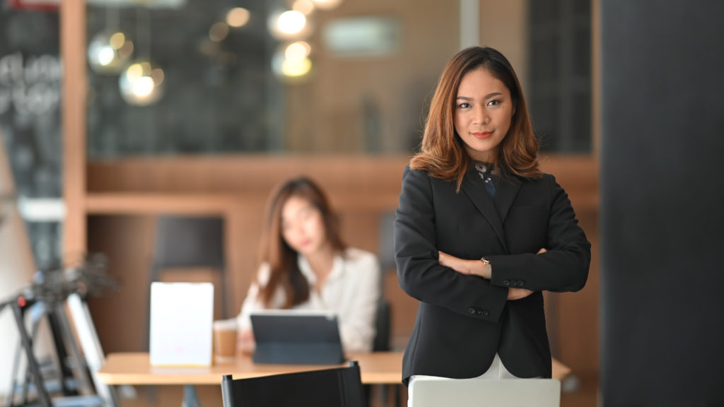 Confident woman CEO standing on front of office workplace.