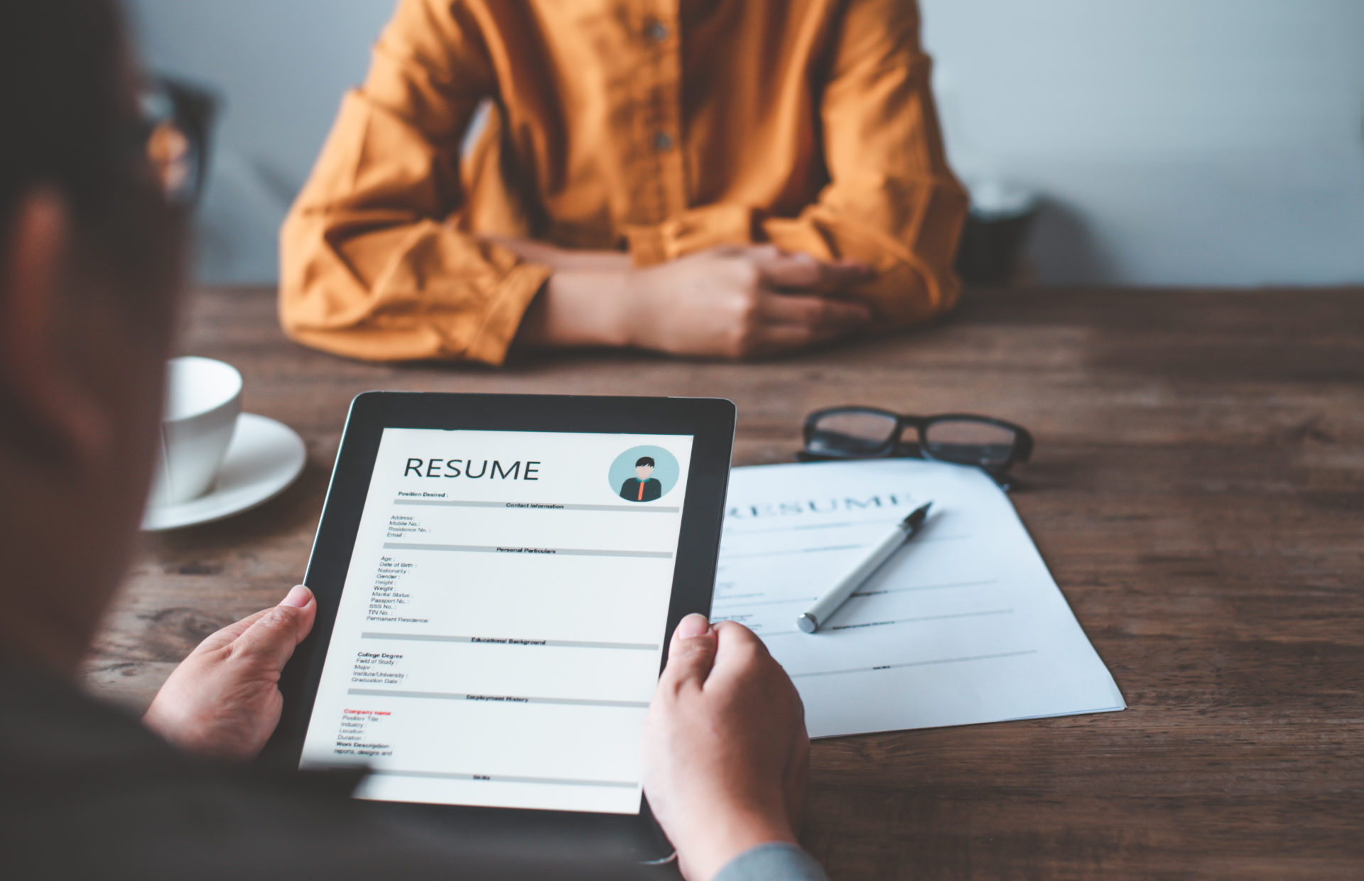 Hiring manager looking at a resume at a desk during a job interview