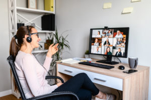 New remote employee is have a meeting with her team using a headset, she is sitting relaxed and smiling