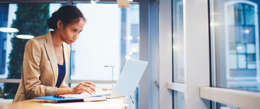 Sales woman making business report about increasing income and sales of company using data from web site via modern laptop computer