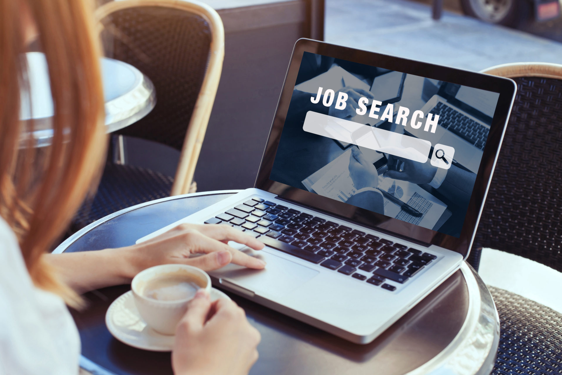 Woman on her laptop with a cup of coffee looking online at different job opportunities