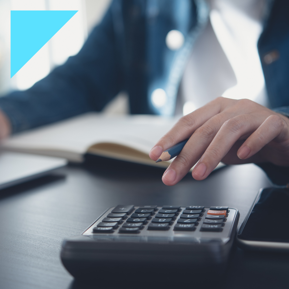A close-up of a professional using a calculator while holding a pencil, with an open notebook in the background, representing the process of calculating labor costs.
