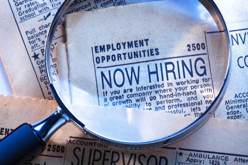 Magnifying glass over a newspaper section that shares a recruiting message