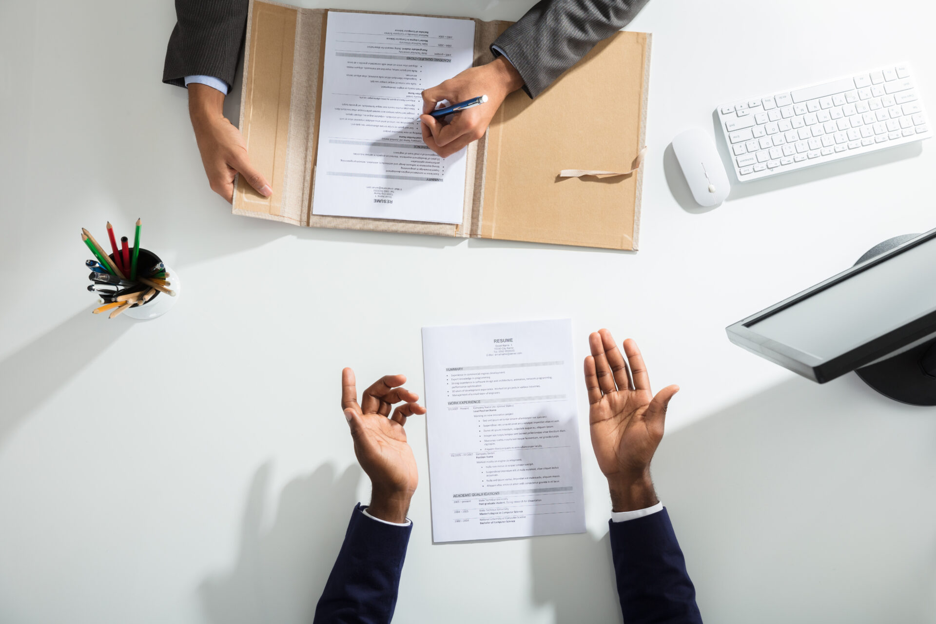 Elevated view of recruiter and job candidate during in interview. Hand on resume sitting at a desk