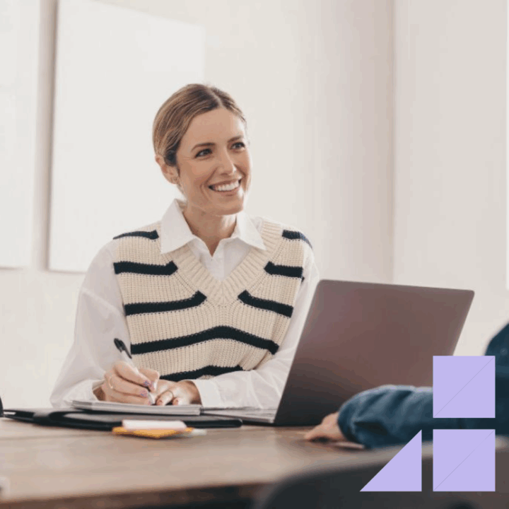 Female full cycle recruiter interviewing a male professional at her desk with laptop open and writing notes