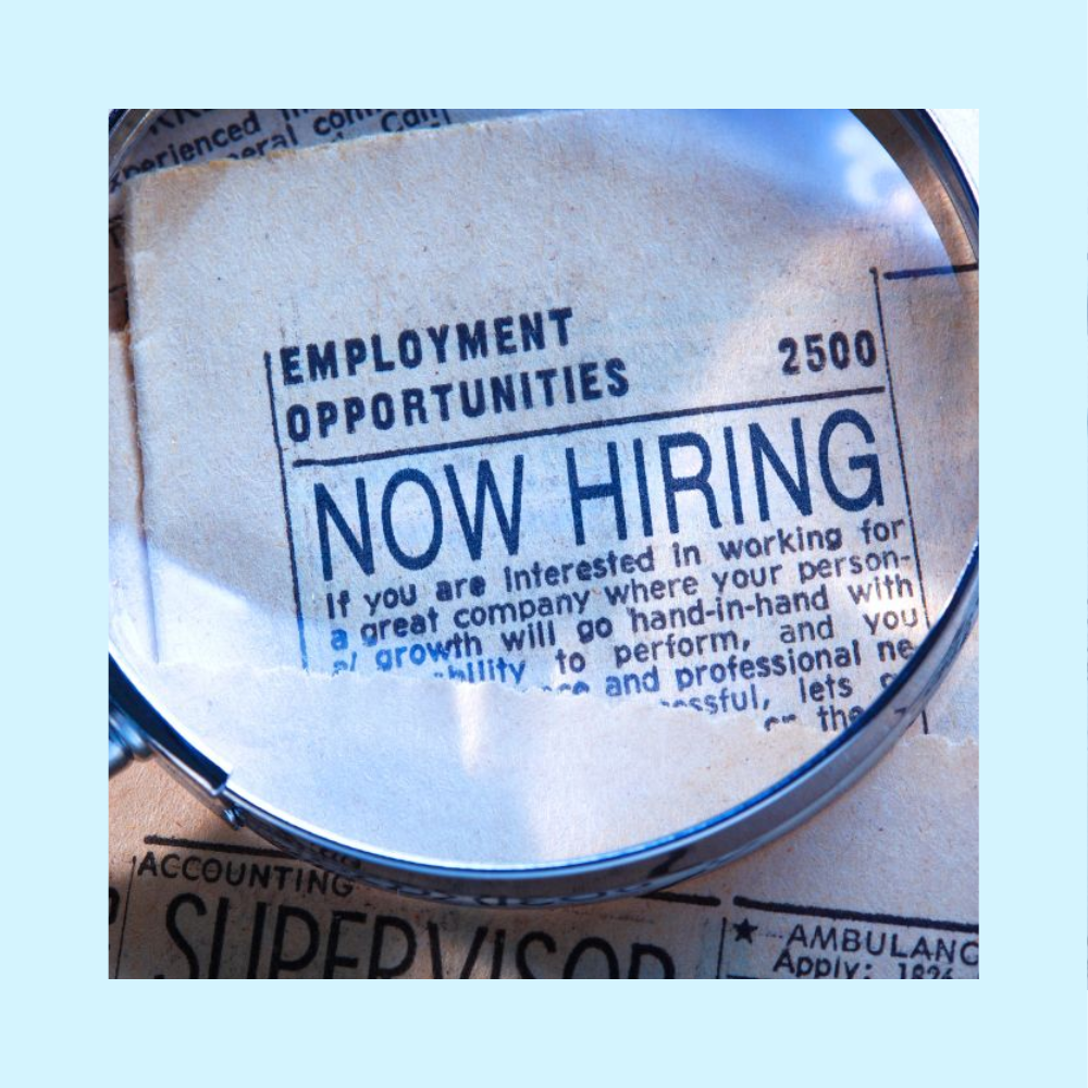 Magnifying glass over a newspaper section that shares a recruiting message