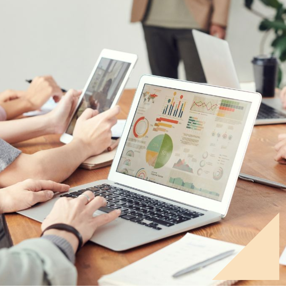 Five professionals with laptop open doing a skill gap analysis sitting around a rectangle wooden desk