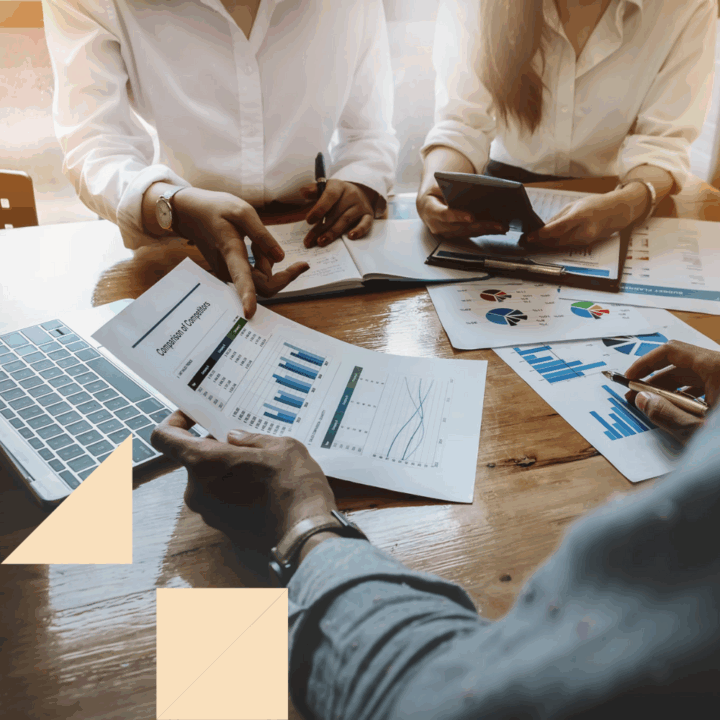 Professionals gathered at a table looking at sheets of paper with different graphs of recruiting metrics