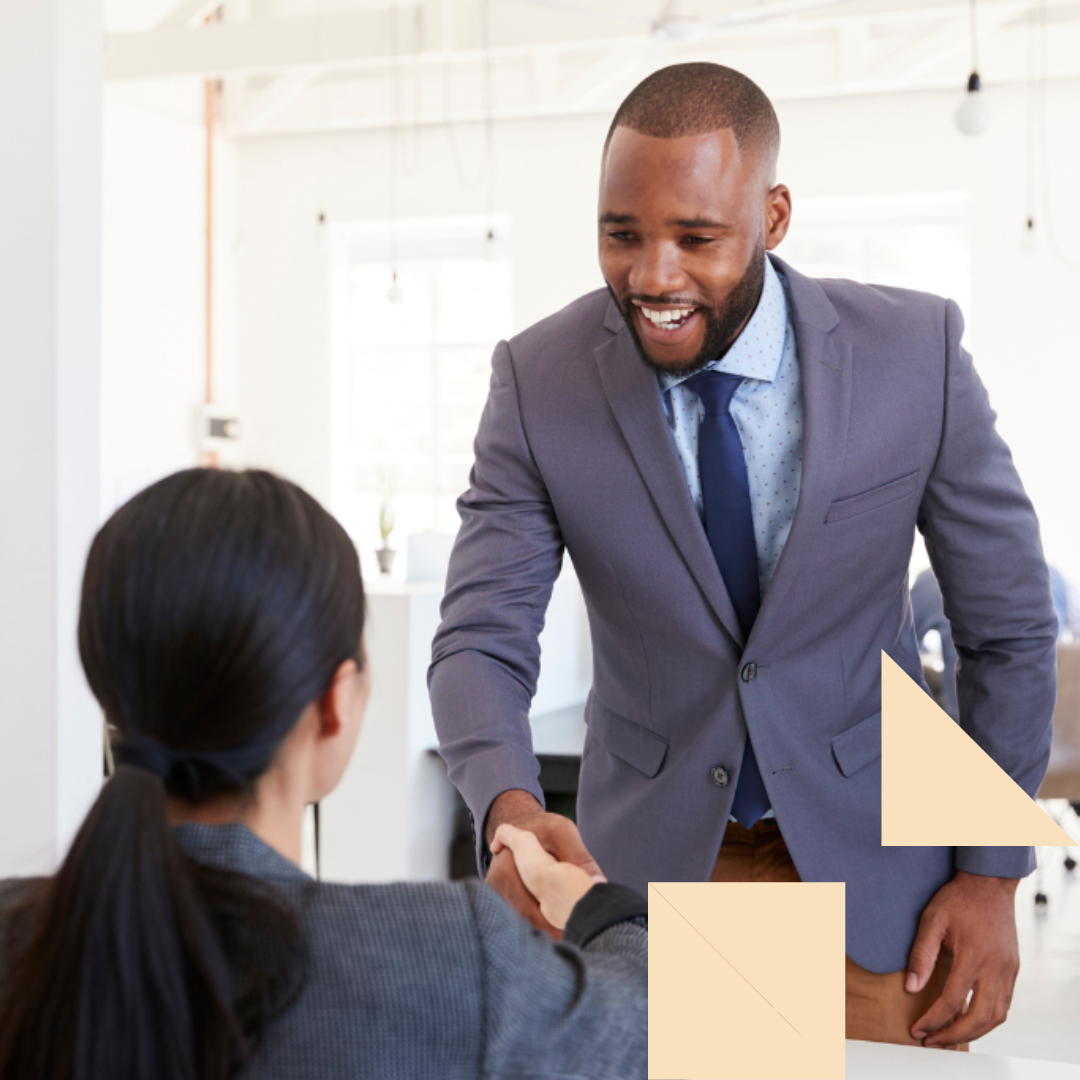 Male independent contractor in a suit shaking hands with hiring female hiring manager during an interview