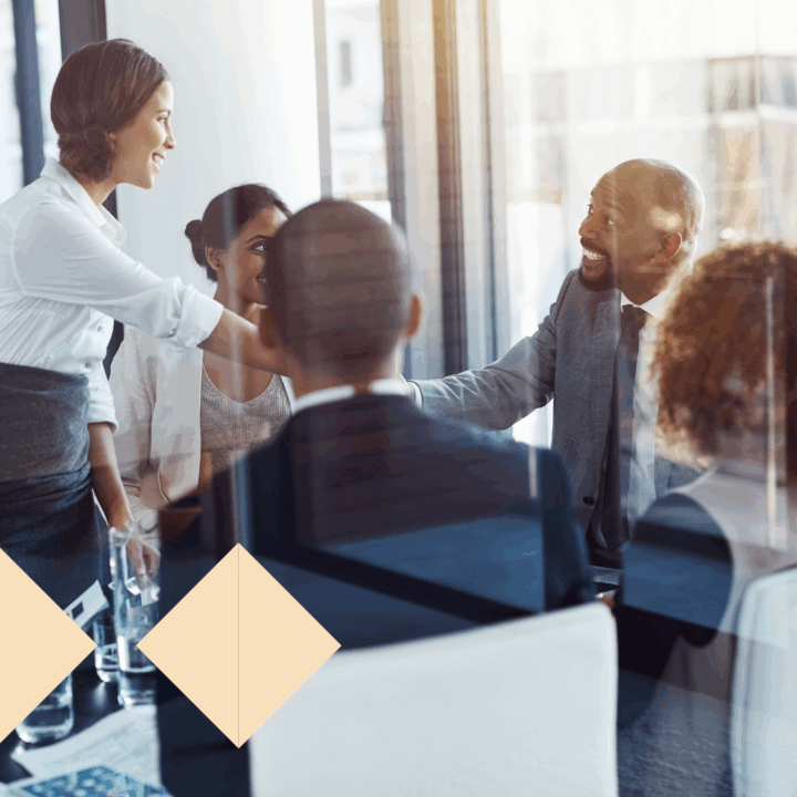 Executives shaking hands during a boardroom meeting, representing successful C-level recruitment and partnership. The group appears engaged and collaborative, symbolizing effective executive search and leadership hiring.