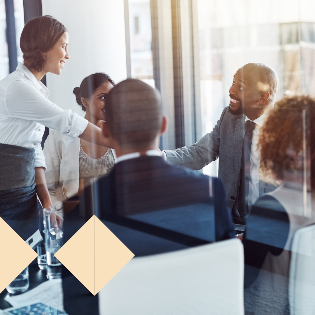 Executives shaking hands during a boardroom meeting, representing successful C-level recruitment and partnership. The group appears engaged and collaborative, symbolizing effective executive search and leadership hiring.
