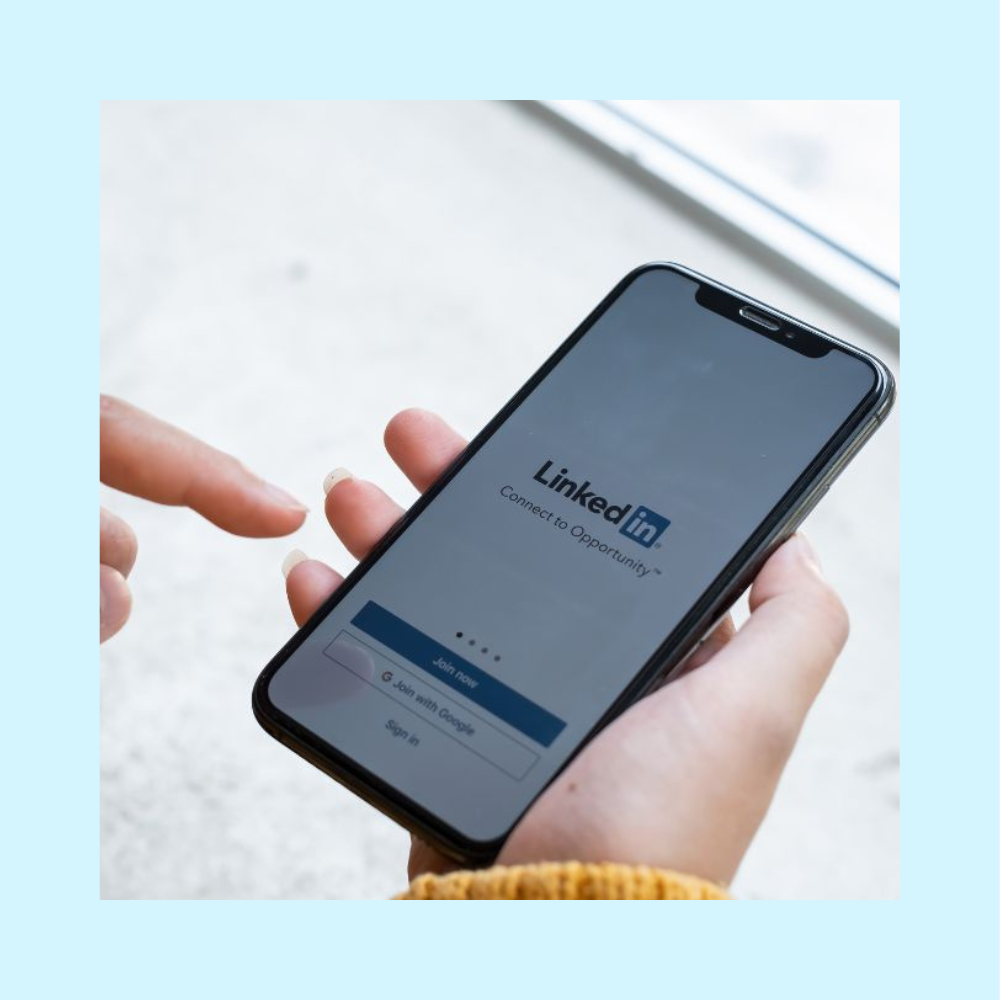 Professional holding an iPhone with the LinkedIn login open