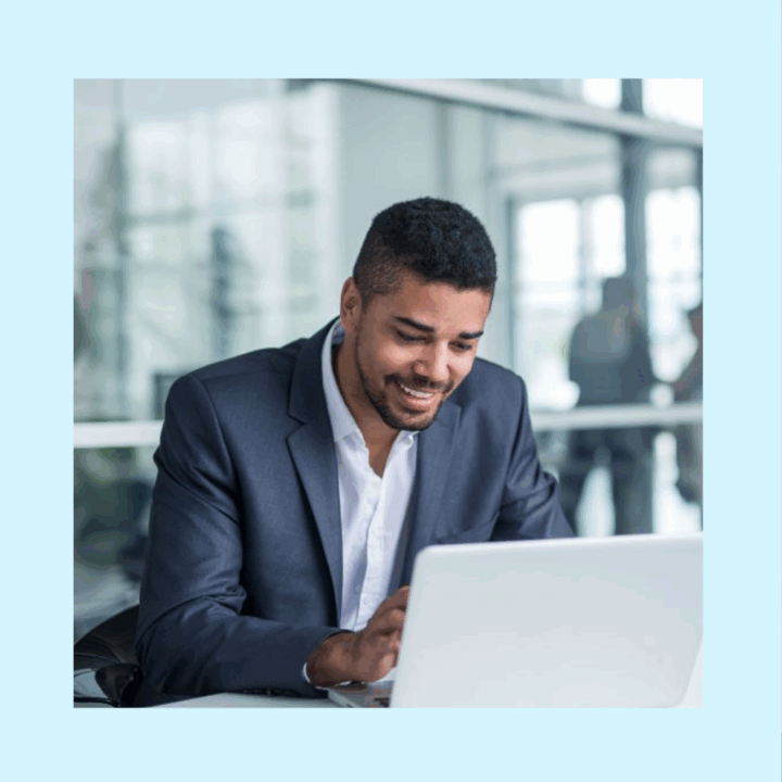 Male contract employee in a suit working behind his white laptop at ma white desk in a modern office