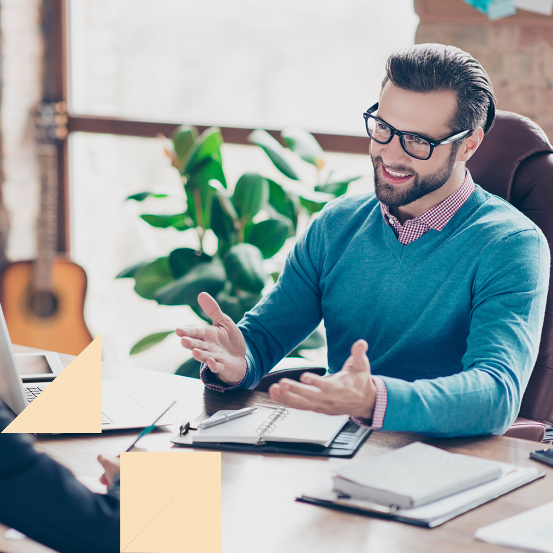 Two professionals sitting across from each other at a desk and talking