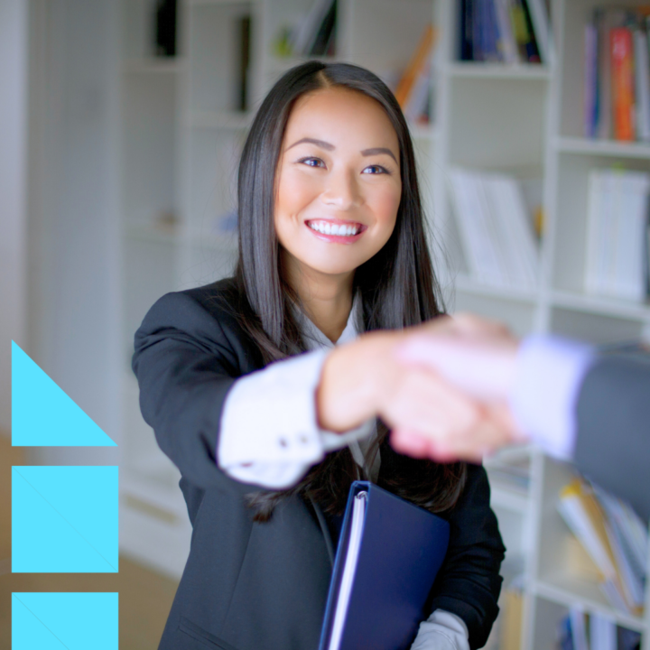 Young female professional in a black suit standing up and shaking the hand of her female interviewer making a good impression at a job interview
