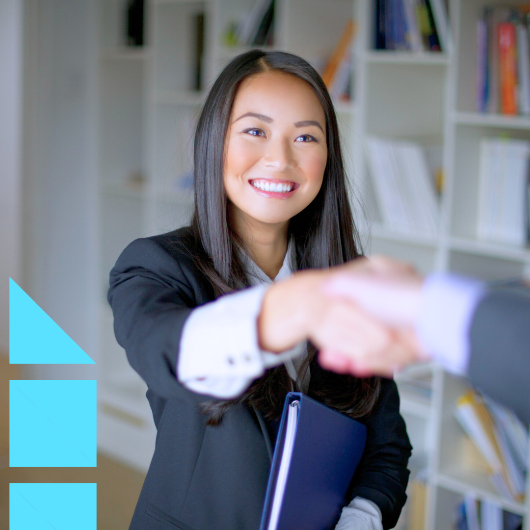 Young female professional in a black suit standing up and shaking the hand of her female interviewer making a good impression at a job interview