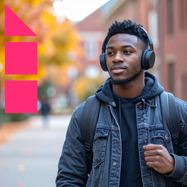 Young man wearing headphones and a backpack walking outdoors in an autumn campus setting