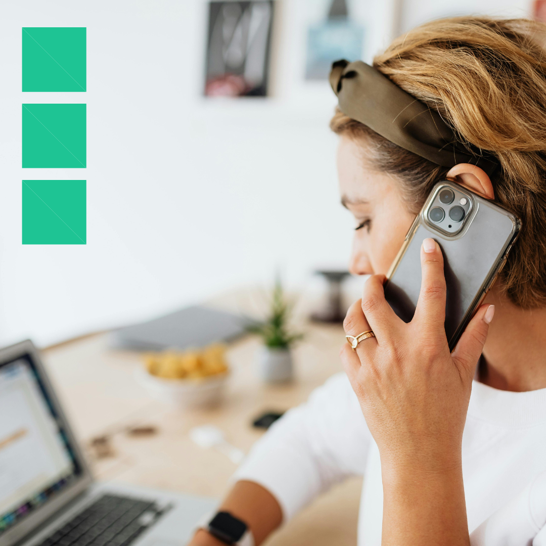 A woman at her desk talking on the phone while looking at her laptop, appearing to withdraw from an interview process.