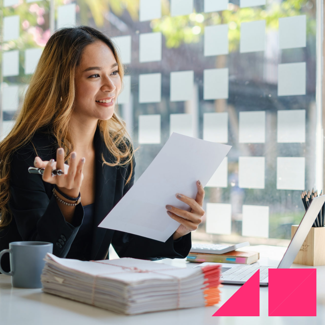 Female hiring manager conducting a skill based interview at her desk with a stack of hiring assessments