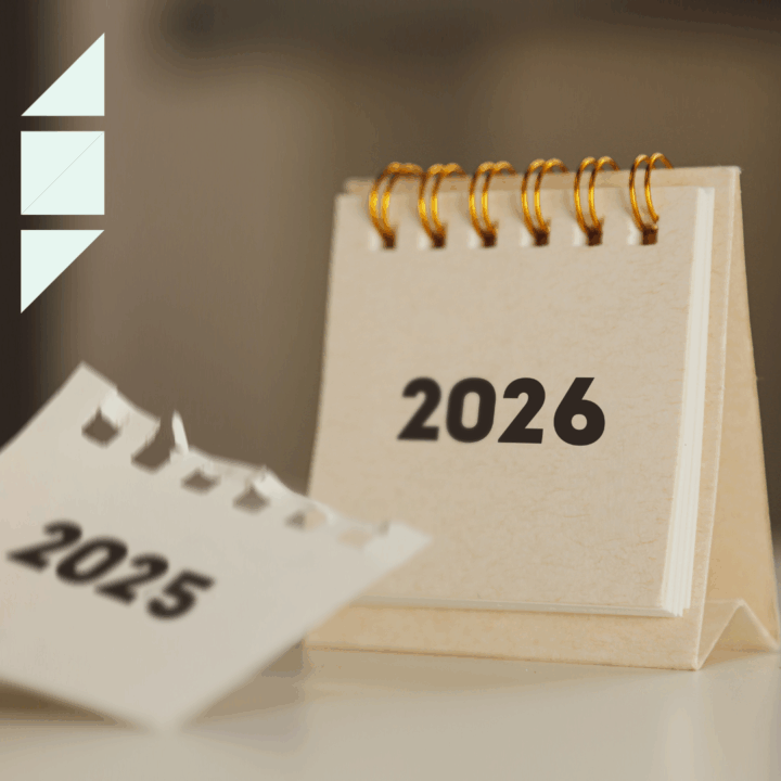 A small desktop calendar flipping from 2025 to 2026, with the 2025 page torn off in the foreground