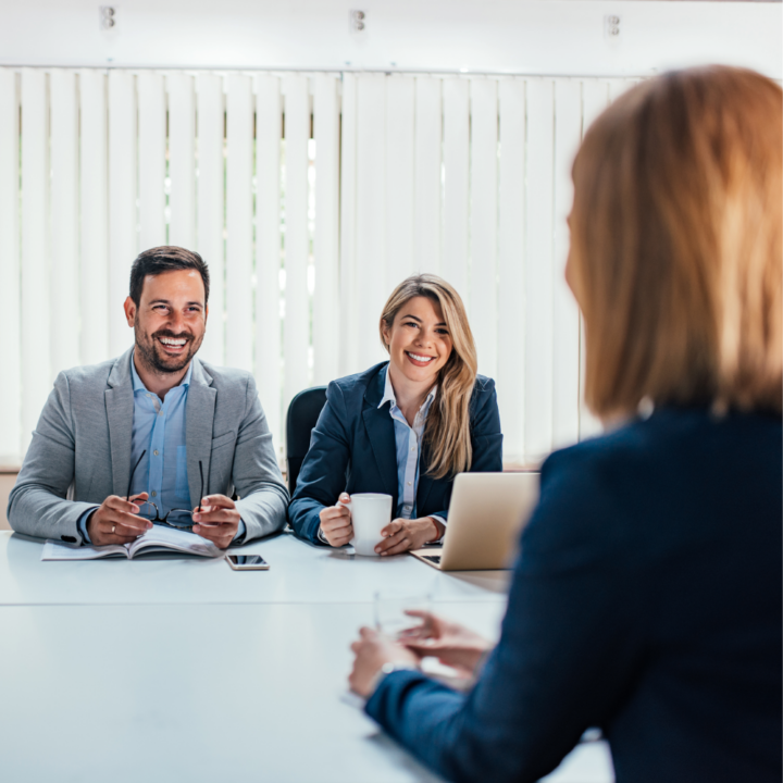 A job seeker participating in a panel interview with two smiling interviewers in a professional office setting, creating a welcoming and engaging atmosphere.
