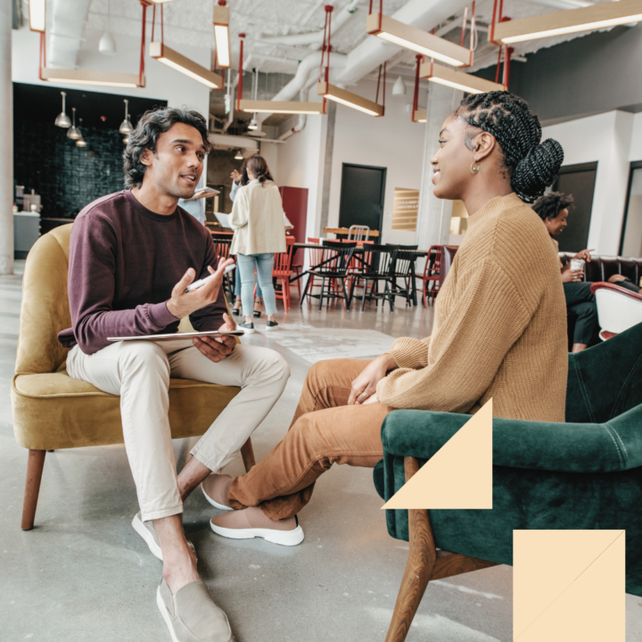 Two professionals engaged in a conversation during an internal interview in a modern, open-concept office space.