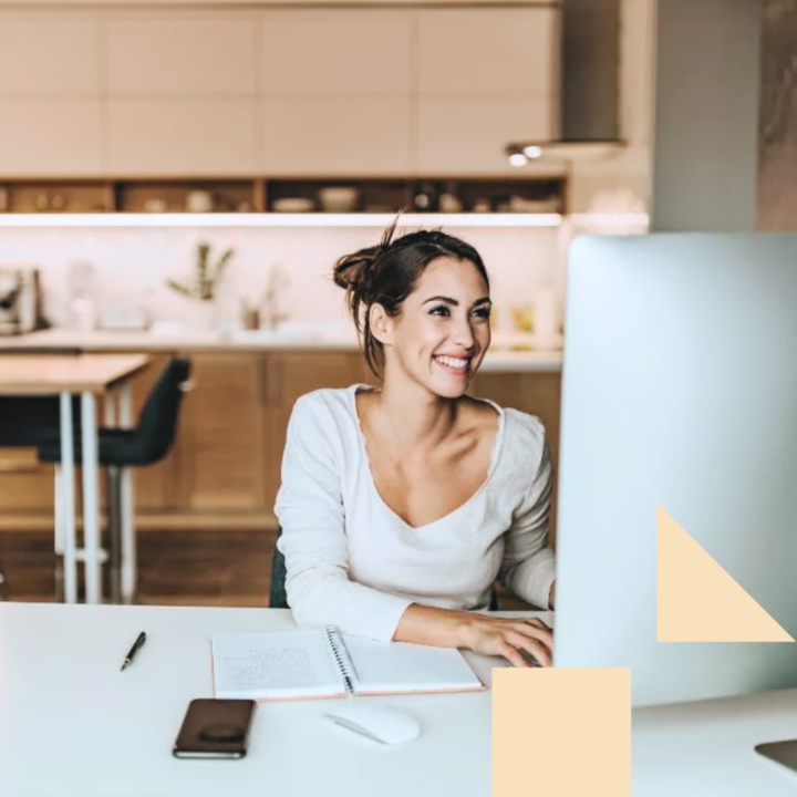 Smiling woman at home on her desktop computer searching for side hustles
