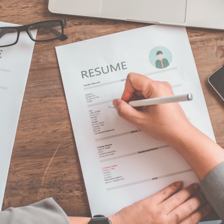 Woman professional filling out her resume summary on the job application form sitting at a wooden desk with laptop