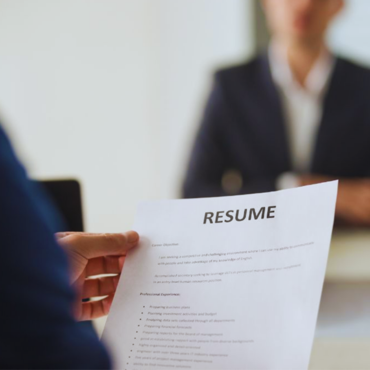 Male executive in a suit handing his resume to female hiring manager across a white table