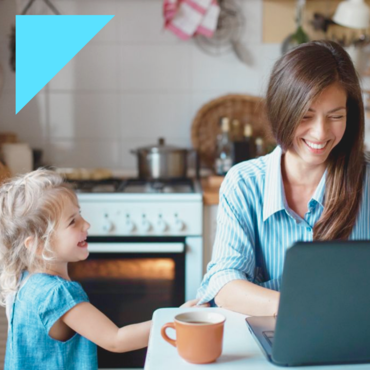 Working from home mom typing on her laptop in her kitchen sitting next to her toddler daughter