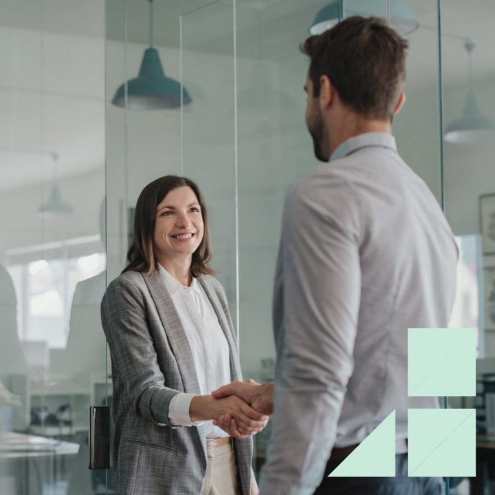 Smiling manager standing outside of her office shaking hands with a new employee after an interview for a direct hire position